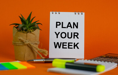 White note with inscription 'plan your week' on beautiful orange background, colored paper, metalic pen, yellow marker,  flowerpot with a plant and calculator. Business concept.
