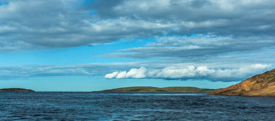 Seascape. View of the Islands, low clouds and clear sky from the water. Panoramic background image.