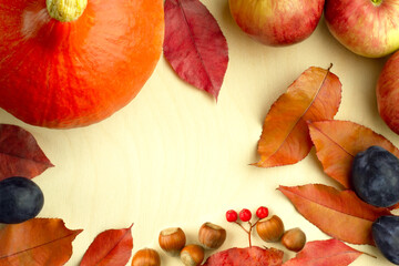 Autumn harvest - pumpkin, berries, apples, plum, hazelnuts and leaves on a wooden background. Thanksgiving Day. Fall composition. Flat lay with copy space