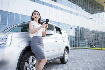 Fototapeta na wymiar a young, beautiful, emotional business woman, standing by the car and talking on the phone