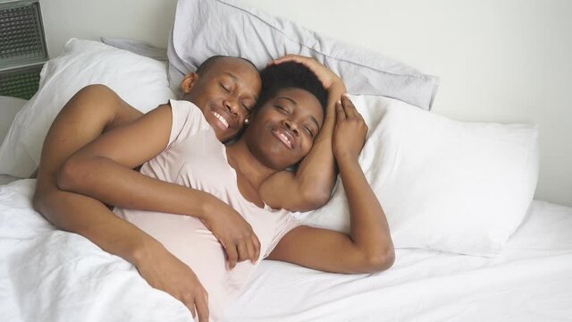 Happy afroamerican married couple lie on bed, pregnant wife and handsome man expecting baby, full happy family.