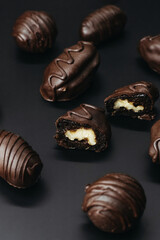 Handmade chocolates with nut inside on dark background.