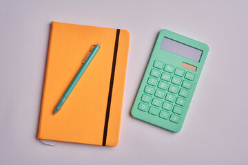 calculator with pen and yellow notepad on white background. office tools