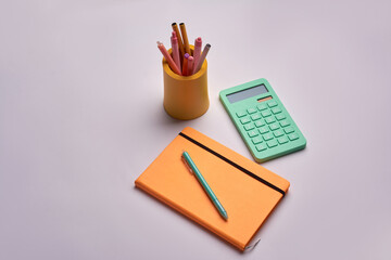 calculator with pen and yellow notepad on white background. office tools