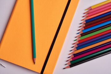 colored pencils and notepad on a white background