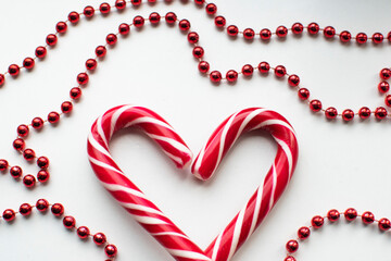 Obraz premium Christmas candy in the shape of a heart among Christmas garlands on a white background. the view from the top. decoration for Christmas