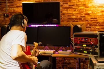 back of male musician enjoy playing electric guitar in home recording studio