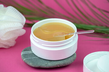 golden under eyes patches in a white container, anti aging skin care, female body care background, pink backdrop