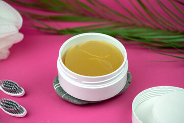 golden under eyes patches in a white container, anti aging skin care, female body care background, pink backdrop