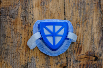 A blue respirator lies on a wooden table, top view.