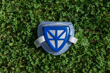 A blue respirator with an elastic band lies on the grass.