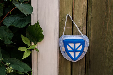 A blue respirator hangs on a wooden wall in the garden.