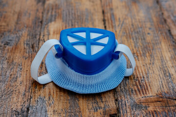 A blue respirator lies on a wooden table, front view.