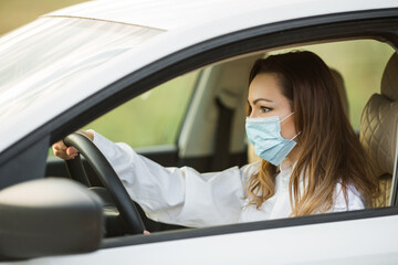 beautiful young woman in medical mask driving a car