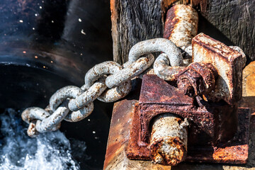 Close up image of old rusty bollard with chain on the pier.