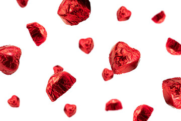 Sweet chocolate heart shaped candy wrapped in red foil papper on white background. Flying candy heart shaped. High quality photo