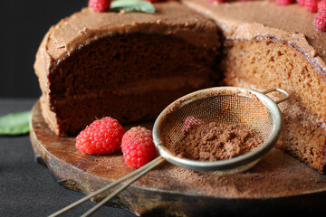 Chocolate cake with raspberries. Cake on a dark background. Sieve with cocoa powder.