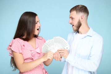 Happy young couple with dollar banknotes on blue background