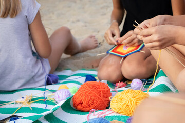 Hand weaving mandalas. A teacher on the beach shows her students how to weave decorative patterns....