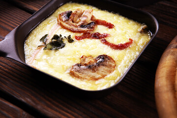 Delicious traditional Swiss melted raclette cheese served in individual skillets with salami and bacon