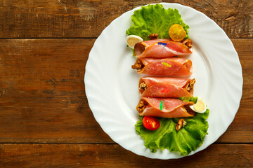 Ham rolls on a plate with quail eggs salad on a wooden table. save a place.