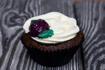 Chocolate muffins with cream flower. Lies on pine boards painted black and white.