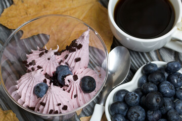 Zephyr in a glass. With biscuit and blueberries. Next to it is a cup of coffee and a saucer of blueberries. Among the maple leaves. On pine boards painted black and white.