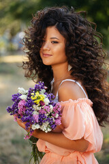 Curly-haired Korean woman with a bouquet of wildflowers in the park - 376742737