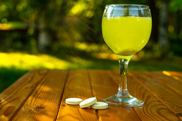 Glass glass with fizzy medicine and pills on the table