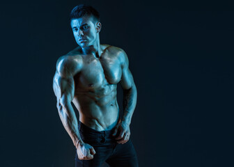 Fototapeta na wymiar Muscular model sports young man on dark background. Fashion portrait of strong brutal guy. Sexy torso. Male flexing his muscles.