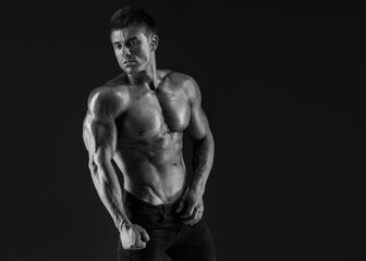 Fototapeta na wymiar Muscular model sports young man on dark background. Fashion portrait of strong brutal guy. Sexy torso. Male flexing his muscles.