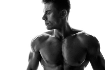 Muscular model sports young man on white background. Black and white fashion portrait of strong brutal guy. Sexy torso. Male flexing his muscles.