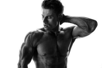 Fototapeta premium Muscular model sports young man on white background. Black and white fashion portrait of strong brutal guy. Sexy torso. Male flexing his muscles.