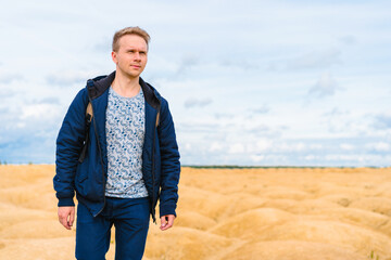 A young blond man in a jacket walks through the desert with sand dunes of bizarre shape