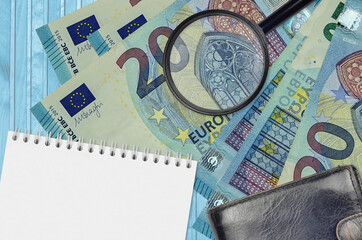 20 euro bills and magnifying glass with black purse and notepad. Concept of counterfeit money....