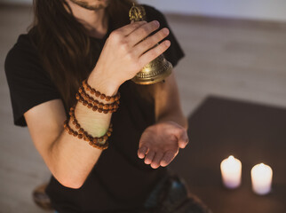 A young male yogi is peacefully meditating, holding a Tibetan Buddhist bowl for yoga and meditation.