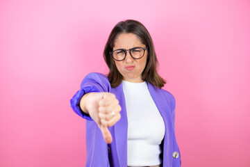 Young beautiful business woman over isolated pink background with angry face, negative sign showing dislike with thumb down