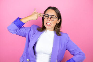 Young beautiful business woman over isolated pink background hooting and killing oneself pointing hand and fingers to head like gun, suicide gesture.