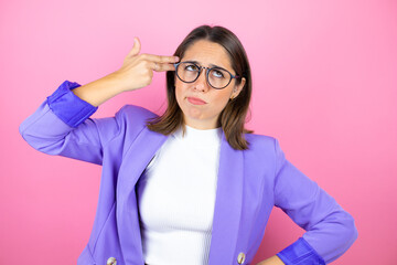 Young beautiful business woman over isolated pink background hooting and killing oneself pointing hand and fingers to head like gun, suicide gesture.