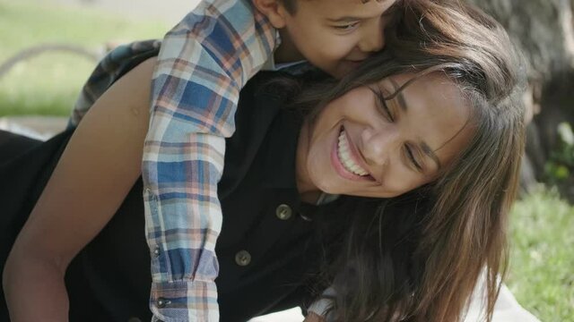 Cheerful smiling african american young adult mother and little kid son laughing at park, mixed race family mom child boy happy faces, closeup portrait