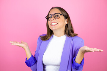 Young beautiful business woman over isolated pink background clueless and confused expression with arms and hands raised