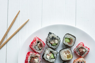 Traditional japanese sushi pieces placed between chopsticks, separated on light blue pastel background. Very high resolution image.