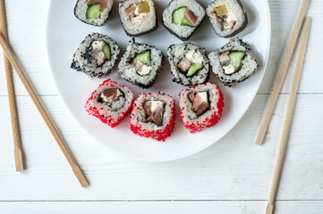 Traditional japanese sushi pieces placed between chopsticks, separated on light blue pastel background. Very high resolution image.