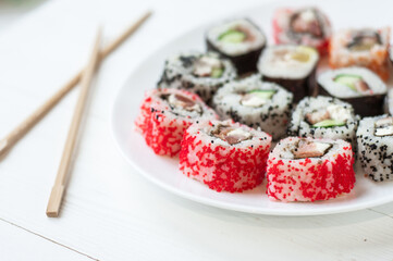 Traditional japanese sushi pieces placed between chopsticks, separated on light blue pastel background. Very high resolution image.