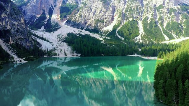Beautiful blue lake, with the reflection of sunlight in the water. Landscape with forest and mountain around the lake in aerial view with a drone 4K