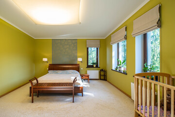 Contemporary interior of luxury bedroom in private house. Wooden furniture and baby bed.