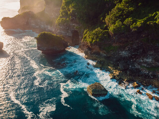 Scenic cliff with rocks, sunshine and blue ocean in Bali. Aerial view