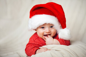 Smiling happy baby in christmas santa's hat and red overalls - 376748198