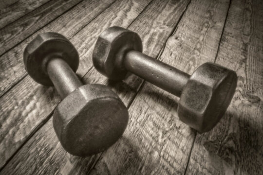 a pair of vintage iron rusty dumbbells on a rustic wood, exercise and fitness concept, soft focus, painterly image shot with a lensless pinhole camera