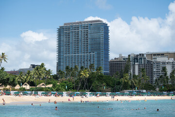 Hotel oceanfront on a sunny white sand beach on Waikiki Honolulu in Hawaii with tourist and beachgoers  enjoying water outdoor activities 